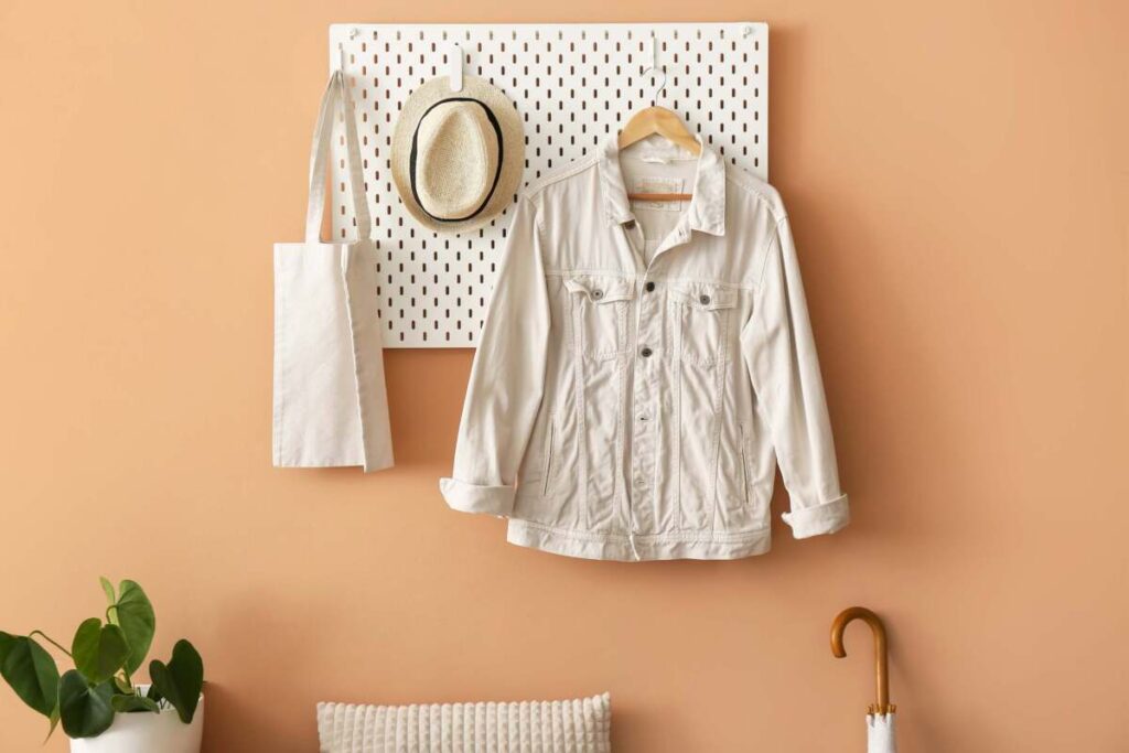 Peg board with coat, bag and hat hanging in an entryway