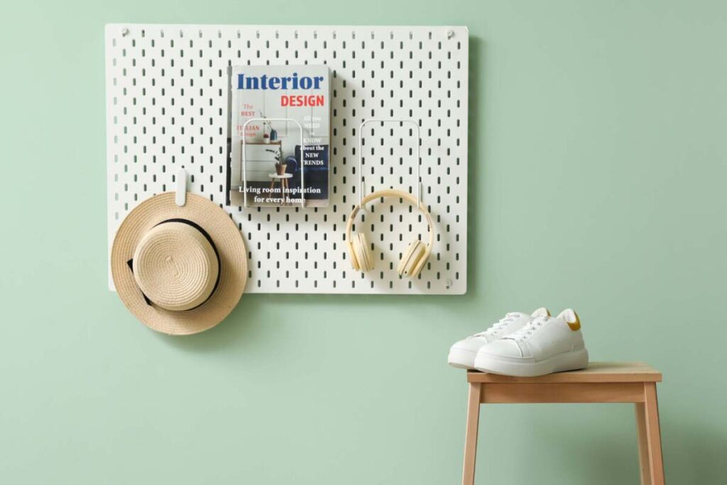 peg board in an entryway with hat, headphones and magazine hanging