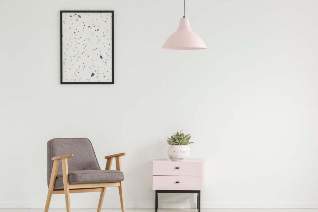 entryway with small table, grey armchair and pink pendant